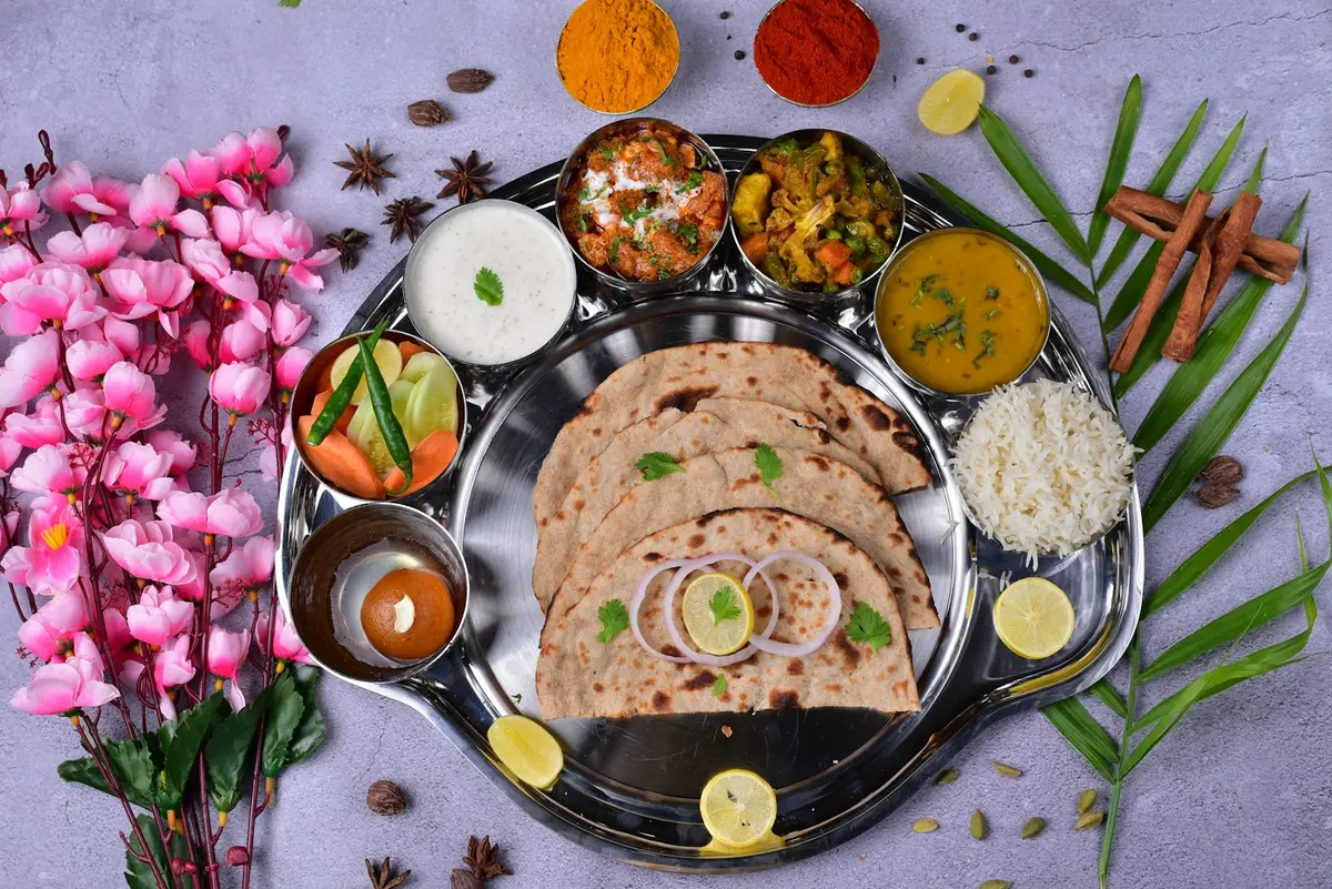 Indian vegetarian thali with roti, rice, dal, vegetables, raita and dessert